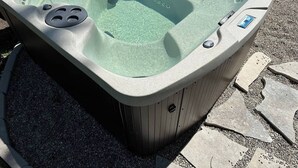 A hot tub with a control panel, a drain, and a safety label. - The CREW House at Bass Lake, IN (Bass Lake)