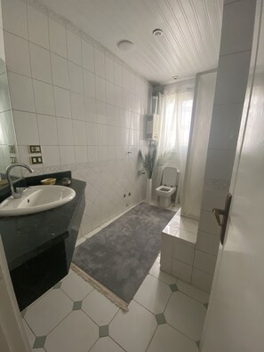 A bathroom with a white sink, a toilet, and a shower area. - Colorful Pyramid Home (Giza Governorate)