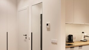 Une cuisine moderne avec des meubles blancs, une machine à café et un climatiseur.