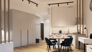 Une cuisine moderne avec des meubles blancs, une table de salle à manger ronde entourée de chaises bleues et une machine à café.