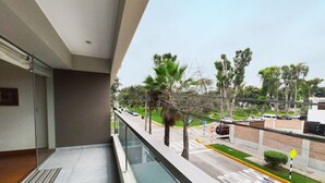 A balcony with a clear view of a street, palm trees, and parked cars. - Beautiful 2,150 sq. ft. 3BR apartment in upscale Chacarilla (Lima)