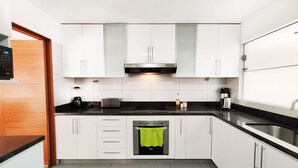 A modern kitchen with white cabinets, a black countertop, a built-in oven, and a coffee maker. - Beautiful 2,150 sq. ft. 3BR apartment in upscale Chacarilla (Lima)
