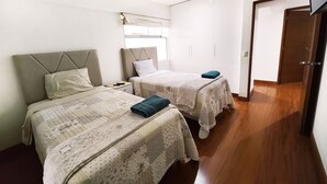 A bedroom with two beds, a wardrobe, and a door leading to another room. - Beautiful 2,150 sq. ft. 3BR apartment in upscale Chacarilla (Lima)