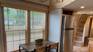 Eine Küche mit einem Holztisch und -stühlen, einem Edelstahlkühlschrank und einer Treppe, die in einen oberen Bereich führt.