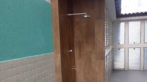 Un espace douche étroit et fermé, doté d’un sol carrelé et d’une porte en bois.
