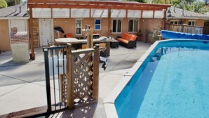 Un jardín trasero con piscina, muebles de patio y una terraza de madera.