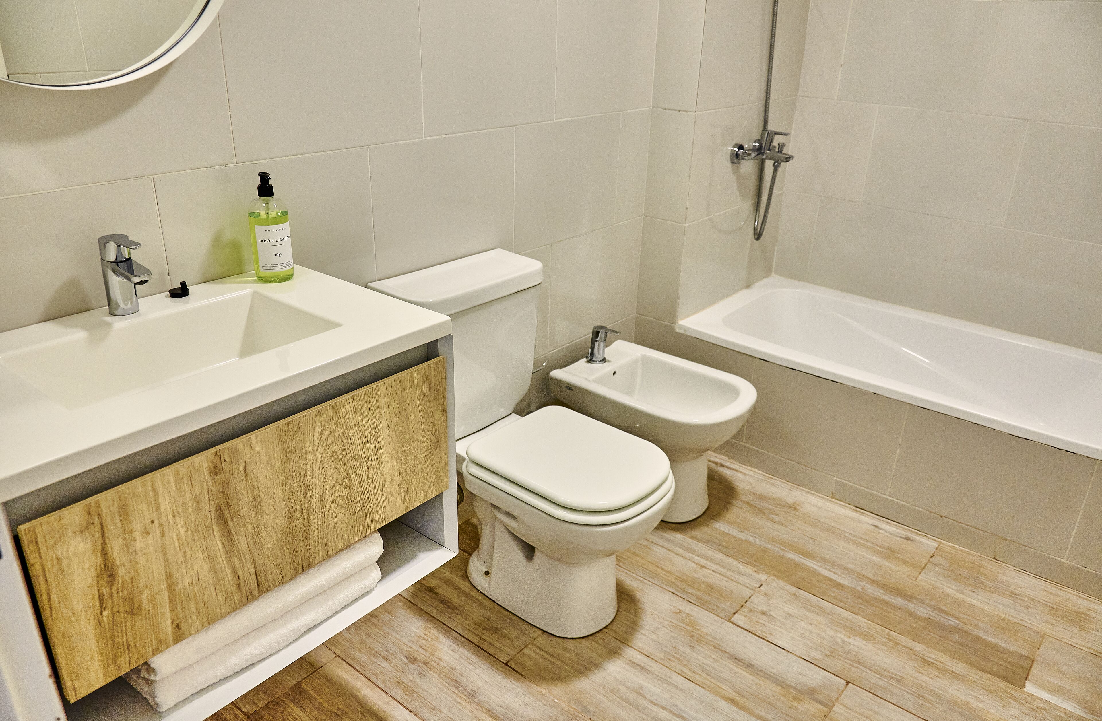 A modern bathroom with a sink, toilet, bidet, and bathtub.