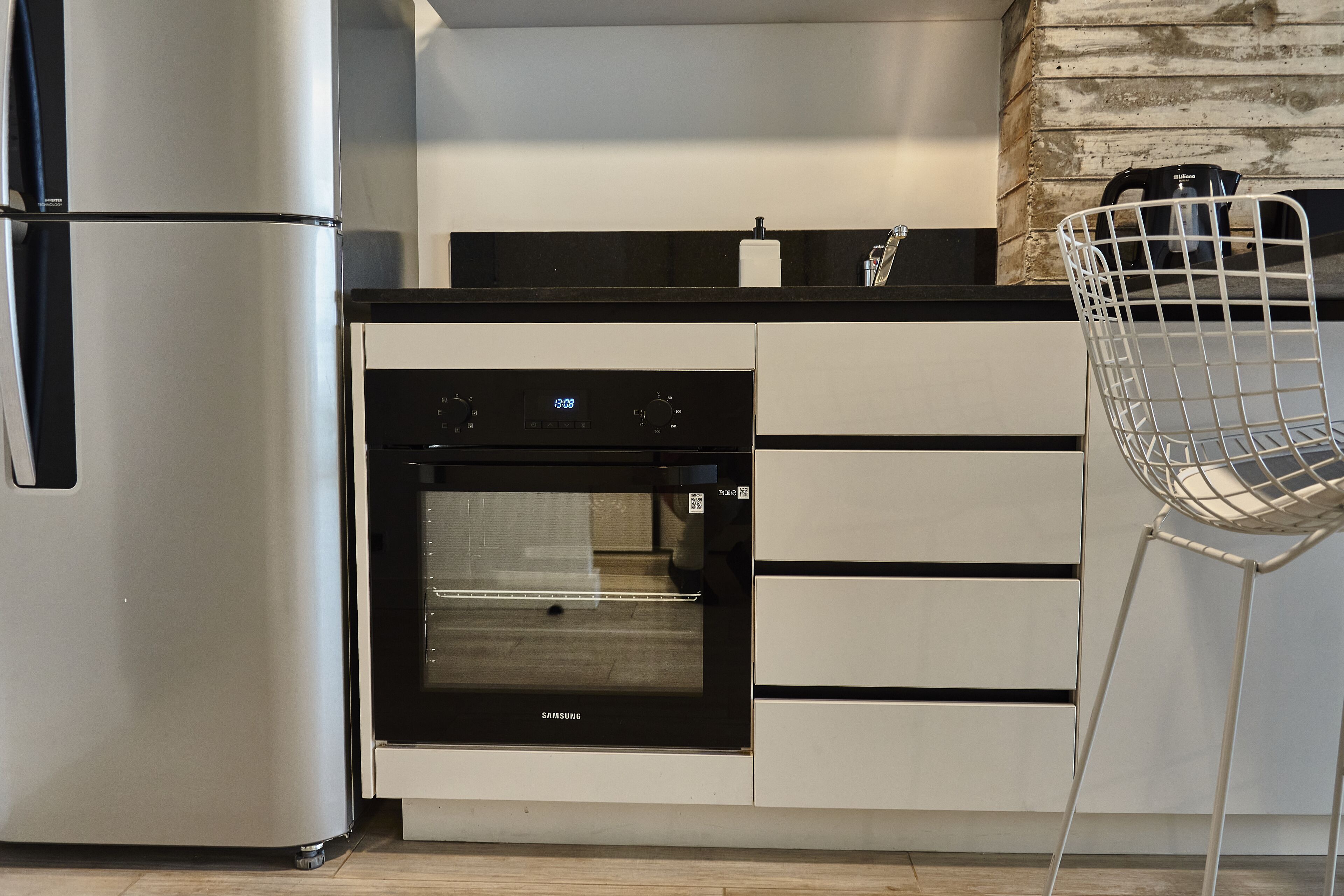 A modern kitchen with stainless steel appliances, a built-in oven, and a white chair.