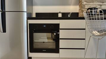A modern kitchen with stainless steel appliances, a built-in oven, and a white chair.
