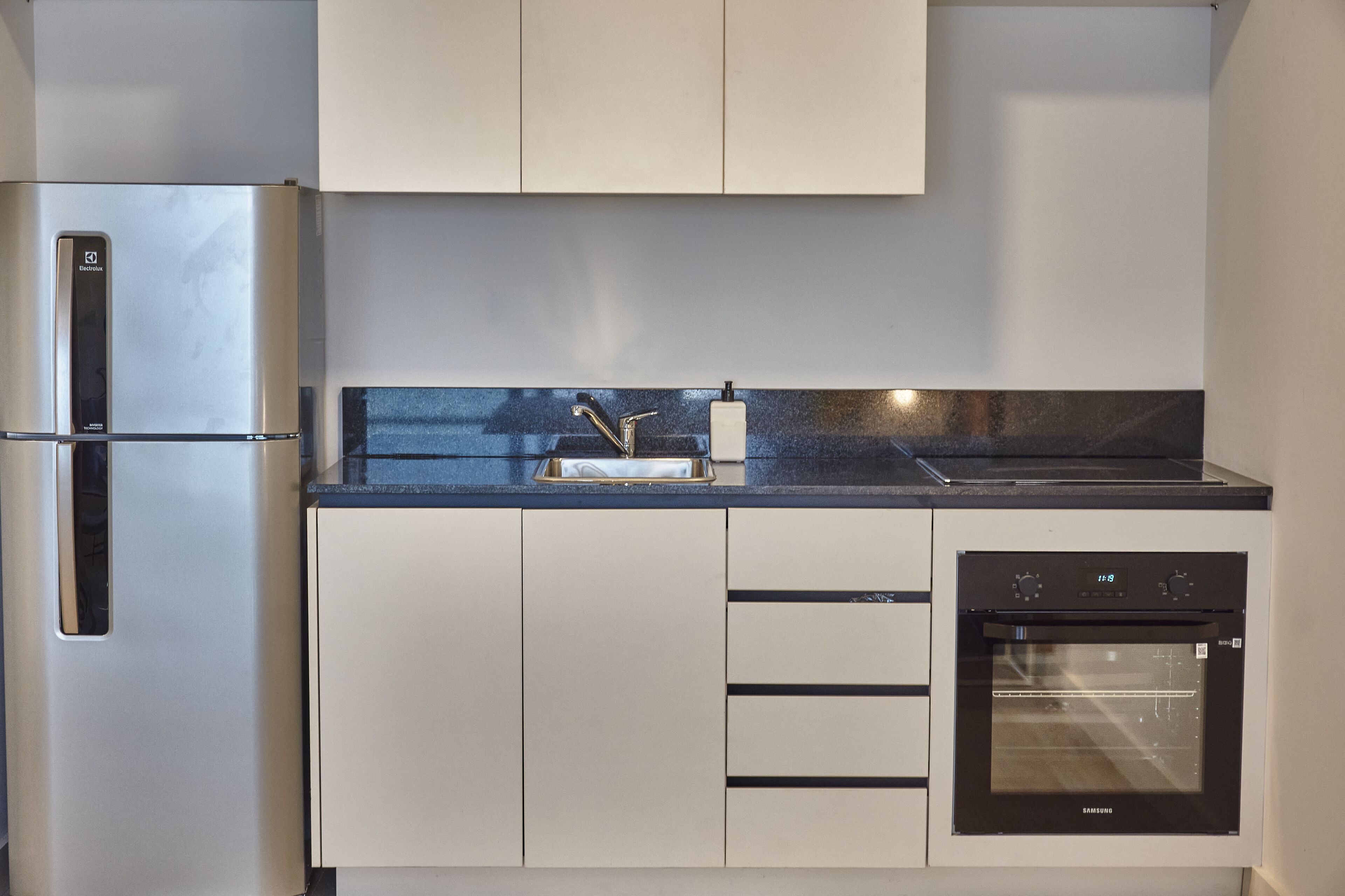 A modern kitchen with a built-in refrigerator, oven, and sink.