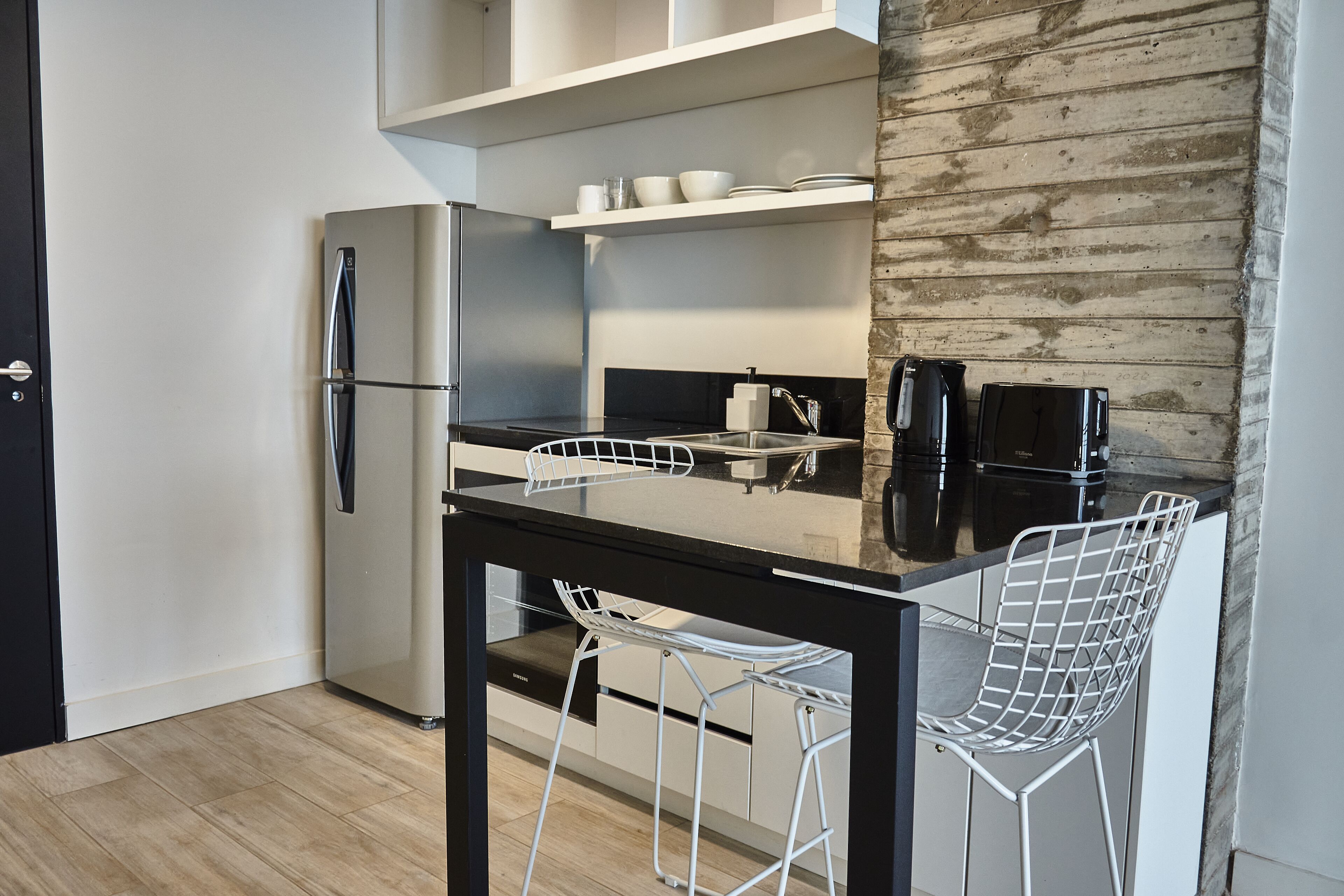 Une cuisine moderne équipée d’un réfrigérateur, d’une cuisinière, d’un évier et de tabourets de bar.