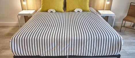 Una cama doble con ropa de cama a rayas, dos mesitas de noche con lámparas y un cabecero de madera.