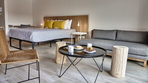 Een moderne hotelkamer met een bed, een bank, een eettafel en een rieten stoel.
