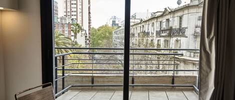 Un balcón con vista a edificios y una silla.