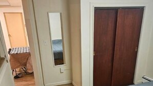 Un dormitorio con suelo de madera, una cama con edredón gris, un aparador de madera, un armario y un espejo.