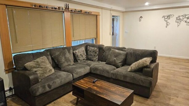 Una sala de estar con un sofá seccional, una mesa de centro de madera y un mapa mundial en la pared.