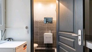 Et lille badeværelse med toilet, håndvask og et skab.