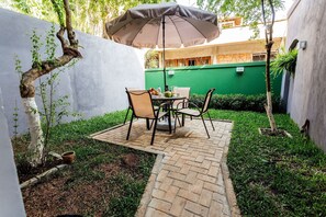 Ein Patio mit Tisch und Stühlen, einem Blumentopf und einer grünen Wand im Hintergrund.