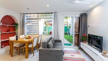 Uma sala de estar moderna com sofá, mesa de jantar e televisão.