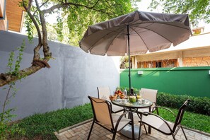 Eine Terrasse mit Tisch, Stühlen und Sonnenschirm.