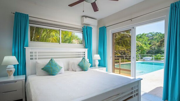 Ein Schlafzimmer mit einem großen Bett, einem Deckenventilator und Blick auf einen Swimmingpool.