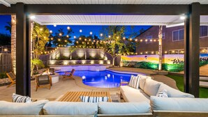 Eine Terrasse im Freien mit Pool, Sitzgelegenheiten und Lichterketten.