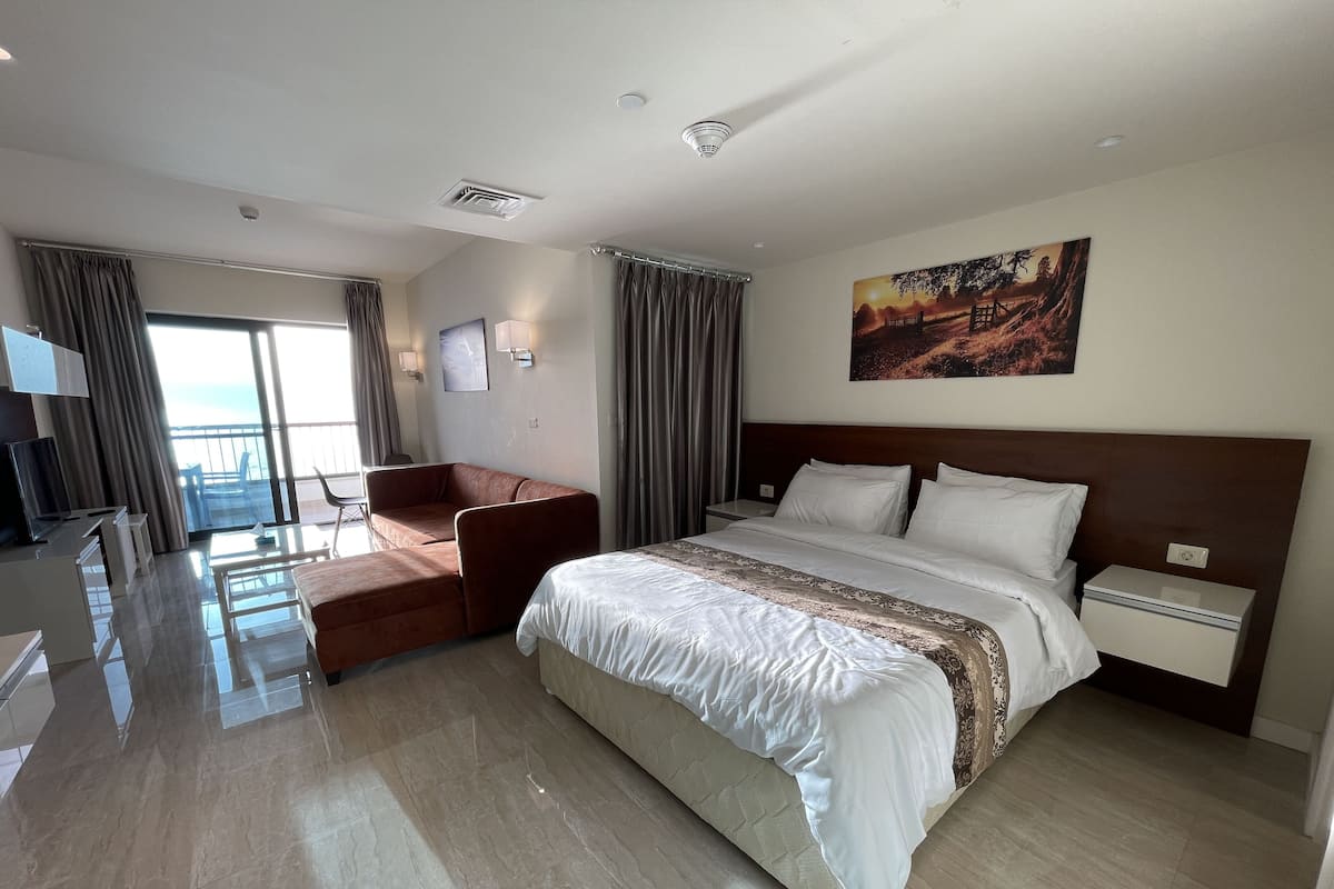 A hotel room with a large bed, a TV, a desk, and a chair.