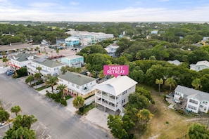 An aerial view of a residential area with multiple houses, including a prominent white house with a balcony and a sign that reads "SWEET RETREAT". - Sweet Retreat by Tybee Vacation Rentals (Tybee Island)