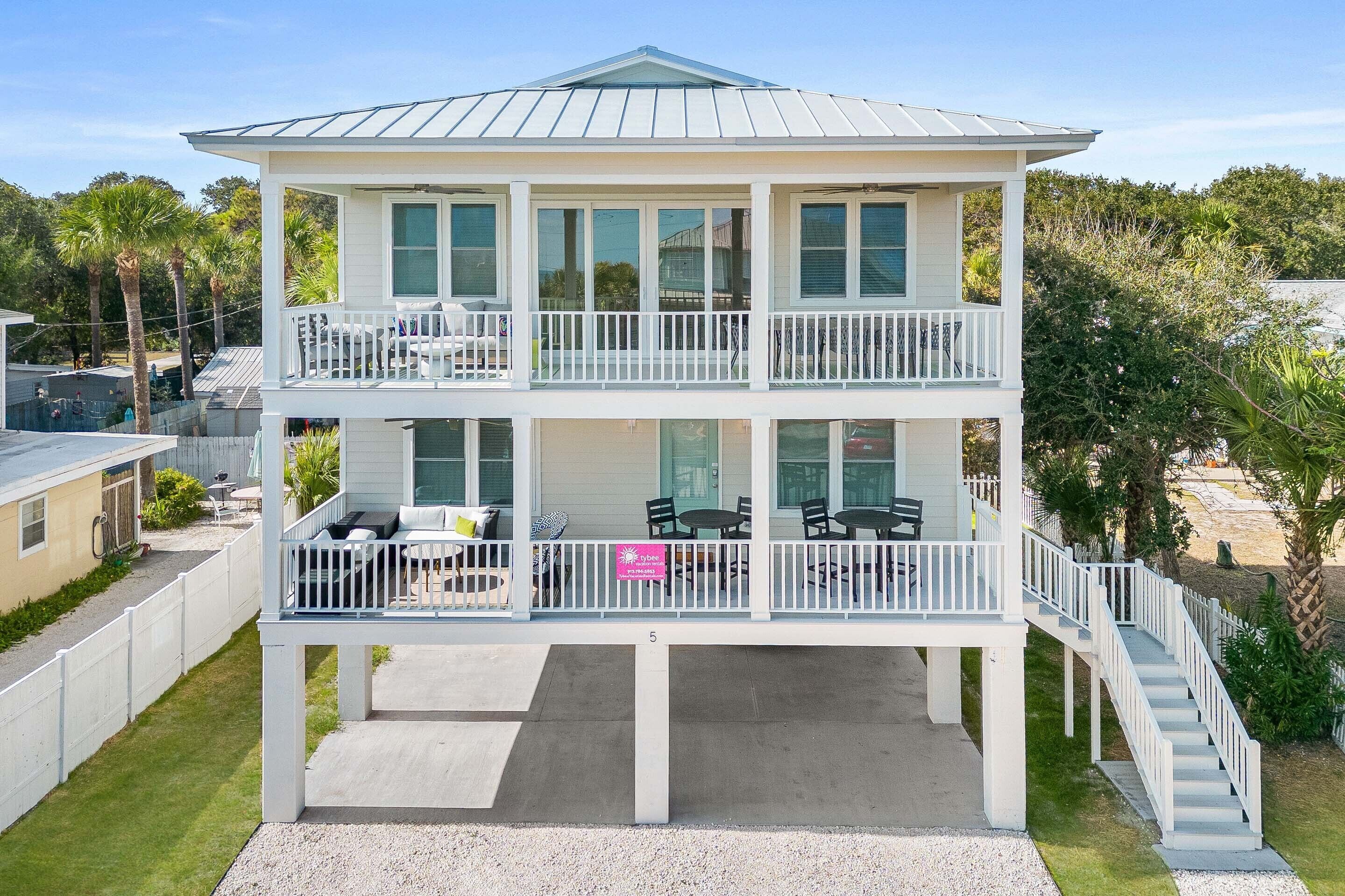 A two-story house with a balcony on the upper level, a covered patio on the ground level, and a staircase leading to the upper balcony.