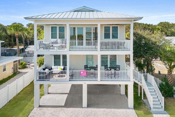 A two-story house with a balcony on the upper level, a covered patio on the ground level, and a staircase leading to the upper balcony. - Sweet Retreat by Tybee Vacation Rentals (Tybee Island)