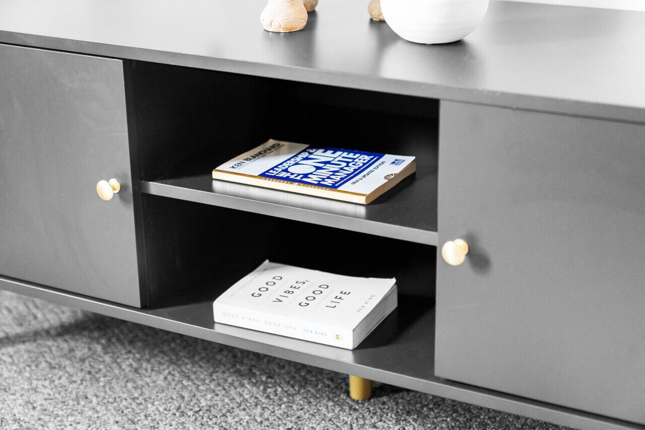 A grey cabinet with two shelves; the top shelf holds a book titled "The One Minute Manager," and the bottom shelf has a book titled "Good Vibes, Good Life."