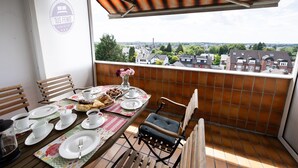 Een balkon met een ontbijttafel, stoelen en uitzicht op de stad.