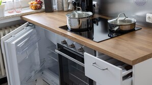 Een keuken met een inbouwoven, een kookplaat en een koelkast.