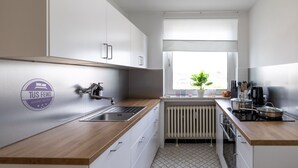 Een moderne keuken met witte kasten, een houten aanrecht, een inbouwspoelbak, een raam met uitzicht en een radiator.