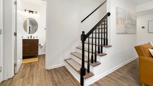 Eine Treppe mit Holzboden und schwarzen Spindeln, die zu einer zweiten Etage führt.