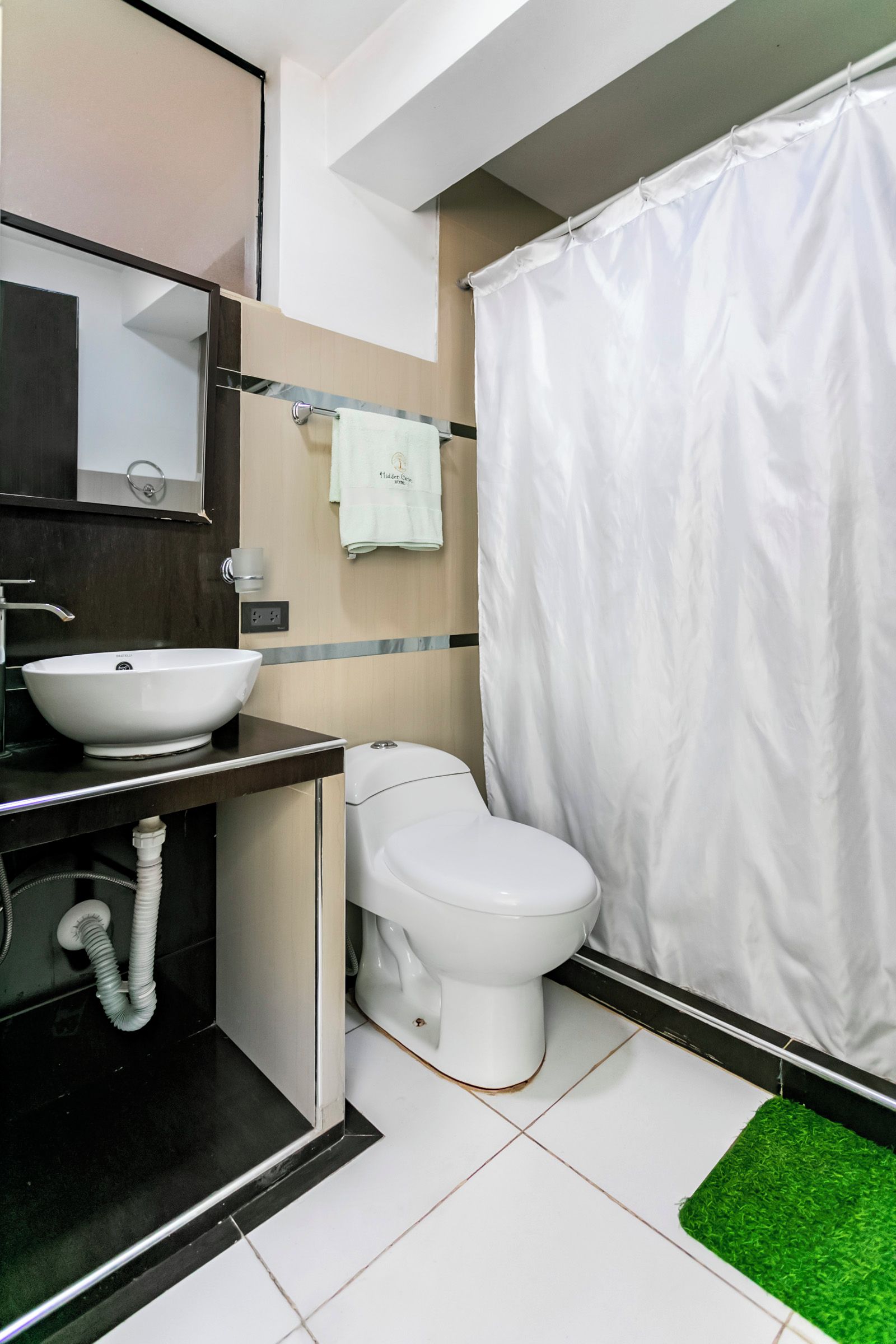 Een moderne badkamer met een witte wastafel, toilet en douchegordijn.