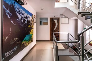 A hallway with a large poster, a staircase, and a door labeled '201'. - Hidden Garden (Cusco)
