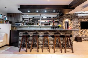 A modern kitchen with a bar area, equipped with stools, a microwave, and various kitchen appliances. - Hidden Garden (Cusco)