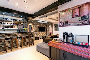 A modern bar area with stools, a counter with various items, and a wall-mounted map. - Hidden Garden (Cusco)