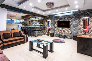Un espacio moderno de sala con bar, sofás, una mesa de centro y una pantalla de televisión que muestra 'NETFLIX'.