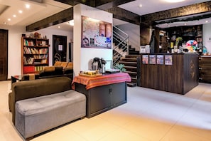 A modern living room with a sofa, a coffee table, a bookshelf, a map on the wall, and a staircase leading to another level. - Hidden Garden (Cusco)