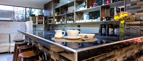 A modern kitchen with a marble island, bar stools, and a variety of kitchenware.