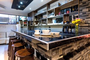 Una cocina moderna con una isla de mármol, taburetes de bar y una variedad de utensilios de cocina.