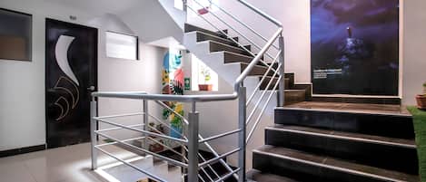 Un interior moderno con una escalera en espiral, un mural grande en la pared y una puerta con un diseño original.