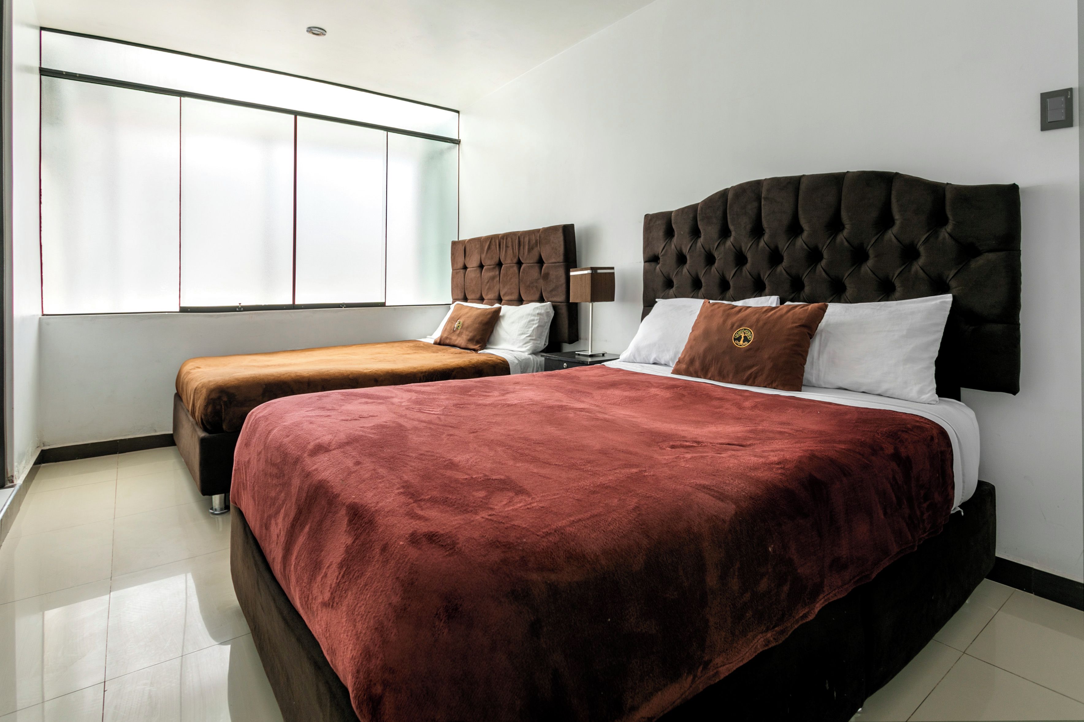 Quarto de hotel com duas camas, uma janela ampla e design moderno.
