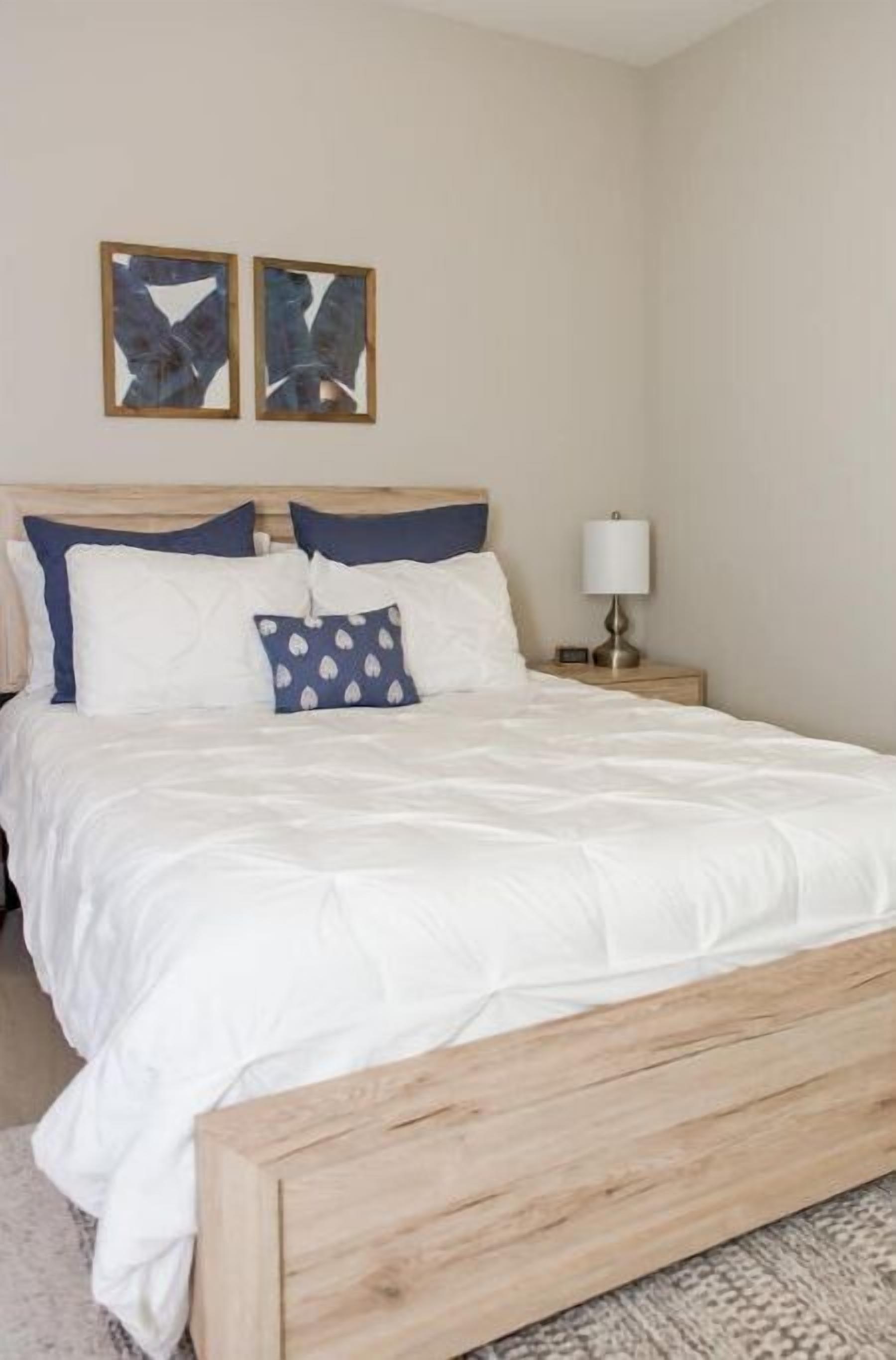 A neatly made bed with white bedding and a wooden headboard.