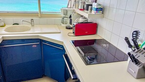 Eine Küche mit Meerblick, einem roten Toaster, einem Spülbecken und verschiedenen Küchengeräten.