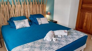 Ein ordentlich bezogenes Bett mit blauer Bettwäsche und dekorativen Kissen, ein Holz-Kopfteil und eine Nachttischlampe.