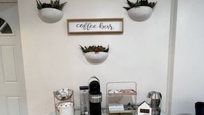Um espaço de café bar com mesa de vidro, máquinas de café e um letreiro que diz 'coffee bar'.