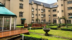 Ein Innenhof mit Holzboden, Bänken und einem Brunnen.